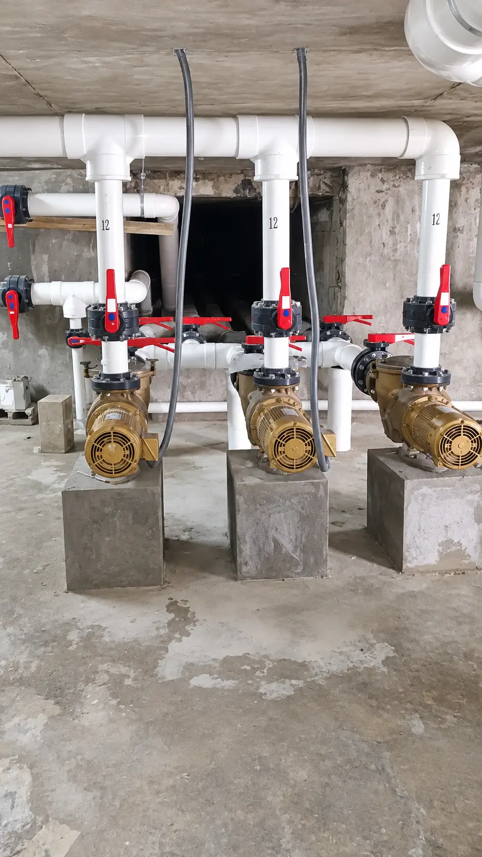 tres-bombas-doradas-sobre-bases-de-concreto-con-valvulas-rojas-compressed